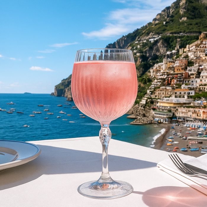 Glass of pink Sarti Rosa Spritz with a scenic view of coastal town and sea in Italy