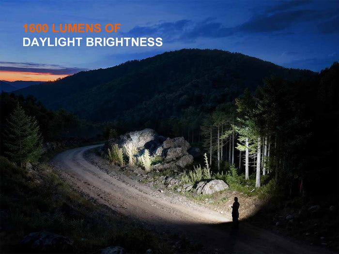 Person walking on a mountain path illuminated by the Fenix E06R PRO RG with text about brightness of up to 1600 lumens.