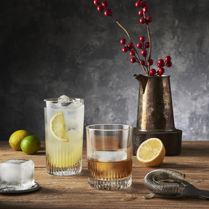 Graphics Cocktail glasses setup with lemon, lime, and ice on a wooden table.